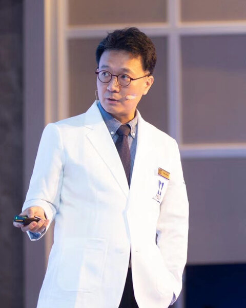 Dr. Min-Hee Ryu presenting in a white coat at RNWOOD.